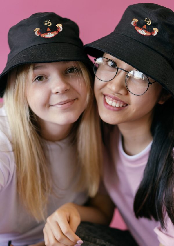 Two teenage girls wearing Myllo embroidered bucket hats made from recycled polyester