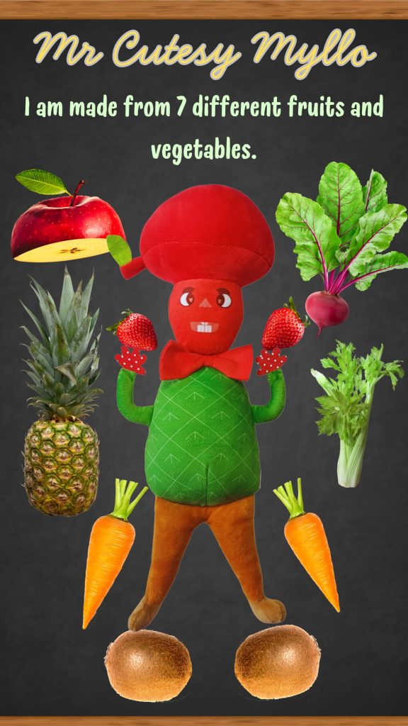 Promotional image of Mr. Cutesy Myllo, a plush toy designed with elements representing seven different fruits and vegetables: a red apple for his head, beetroot, strawberries, a pineapple, celery, carrots, and kiwi, arranged around him against a dark background.